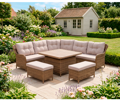 Aruba diningsæt i naturfarvet polyrattan med højt bord, hjørnesofa og to puffer på solrig terrasse i blomstrende have
